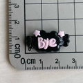 Close-up of a black resin cloud charm with pink stars and 'Bye' text on a scale mat - Black Base Pink BYE