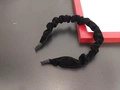 Close-up of a black velvet headband with irregular pleated texture on a dark display - Black
