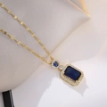 Detailed shot of a gold-toned necklace with square and round blue crystal pendants - Blue Gemstone Necklace