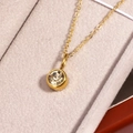 Detailed macro shot of a gold birthstone necklace with a round clear crystal pendant - November Yellow