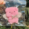 Close-up of a pink resin angel pig squeeze toy with small wings and pearl decoration - Angel Pig