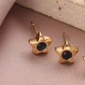 Vue macro de boucles d'oreilles étoiles dorées avec pierre bleue sur fond de pierre - 14k / Or/Bleu