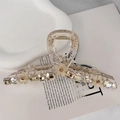 Close-up of a clear hair claw clip decorated with crystals and small flowers on white paper - Champagne