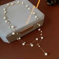 Détail d'un collier de perles vintage avec chaîne dorée sur un écrin en velours - Or-Blanc