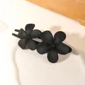 Detail of matte black hair clip featuring double five-petal flowers on a ceramic dish - Double Flower Clip - Matte Black