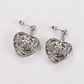 Detailed view of silver hollow heart earrings in polished stainless steel on white - Silver