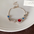 Exquisita pulsera dorada con cristal rojo central y diamantes de colores en un cuenco - Rojo
