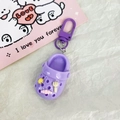 Portachiavi a forma di zoccolo viola con ciondoli colorati su sfondo di carta bianca - Viola
