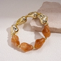 Détail d'un bracelet ethnique perlé avec métal doré et résine ambrée sur pierre - Café Clair