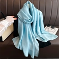 Close-up of elegant light blue satin scarf draped near leather sofa and accessories - Lake Blue