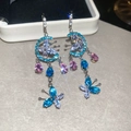 Macro shot of colorful pear-shaped crystal tassel earrings with butterfly motifs - Blue