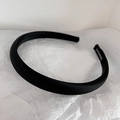 Detailed view of black satin headband on white paper with handmade label tag - Black