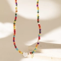 Close-up of colorful beaded necklace with white heart charm and golden letter F pendant - Letter F