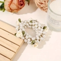 Close-up of white faux pearl hair tie with cream fabric roses and green ribbon leaves - White Flower