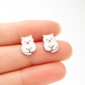 Macro shot of minimalist cat-shaped stainless steel stud earrings held on a finger - Steel