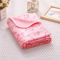 Detail of pink flannel pet blanket with red paw prints folded on a soft white knit base - Carved Pink Paw Print