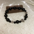 Close-up of black beaded bracelet with silver cross pendant on rustic wooden base - Large / Black