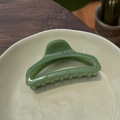 Detailed view of large green perfume bottle hair claw clip on beige ceramic plate - Leaf Green