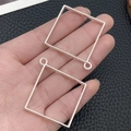 Pair of square silver alloy hollow pendants for DIY jewelry crafting held in hand - Large Square Bezel (22253) / 48x44mm / Bright Silver