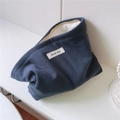 Detailed shot of dark blue corduroy makeup bag with simple wish label and metal zipper - Dark Blue