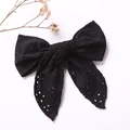Detail of elegant black Broderie Anglaise bow hair clip with embroidery on white background - Black