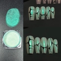 Macro view of metallic green aurora nail powder with decorative nail art display - Aurora Cyan