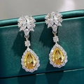 Macro shot of silver teardrop earrings featuring a pear-cut yellow gem and white zircons - Yellow