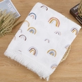 Cotton muslin baby blanket with rainbow prints and fringe tassels on a wooden table - White Rainbow