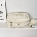 Close-up of cloud quilting texture and top handle on beige cosmetic storage bag - Creamy White
