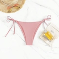 Pink tie-side bikini bottom displayed on marble background with summer beach accessories - Pink