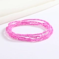Macro shot of multi-layer pink glass seed bead waist chain on white fabric background - Pink Transparent