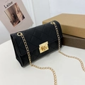 Small black crossbody bag with diamond quilting and a gold chain strap on a magazine - Black