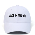 Close-up detail of the black 'MADE IN THE 90'S' embroidery on a white cotton baseball cap - White