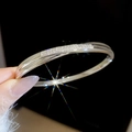 Macro shot of 18k silver plated bangle featuring a rectangular pave set zircon display - Silver-Pave Set Circular Bangle (8#) / [product Attributes]: The Image Shows An Exquisite [product Type] Bangle; [color] Appears To Be Bright Silver; [decoration] The Bangle Has A Rectangular Area In The Center Of The Front Which Appears To Be Set With Small Transparent Zircon Stones Or Diamonds Using A Pavé Setting Technique; [structure] Appears To Be A Polished Metal Ring. [visual Presentation]: The Image Uses A Dark Black Background Which Greatly Enhances The Luster Of The Metal And The Fire Of The Gemstones. The Image Quality Is [high] With Precise Focus And Well-handled Local Lighting And Shadows. The Starburst Effect Enhances The Jewelry's High-end Feel. Aesthetic Appeal Is [high] With An Overall Score Of [8.5]. The Model's Hand Is Presented Naturally And The Overall Visual Flow Is Unified. [text Content]: No Text Content Was Detected In The Image. [logistics Tags]: None [infringement Risk]: The Product Is A General Basic Style Of Jewelry And No Specific Brand Logo Or Infringing Features Were Found. [product Parameters]: The Image Does Not Provide Specific Parameters Such As Weight Inner Diameter Or Material Purity.