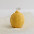 Realistic lemon-shaped yellow scented candle with textured peel and white wick - Vertical Lemon Yellow
