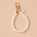 Detalle del llavero de perlas con cierre dorado y elegante colgante de flor esmaltada blanca - Blanco