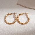 Macro detail of golden twisted rope texture on circular geometric hoop earrings - Gold Twisted