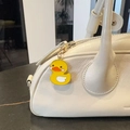 Detail of a yellow enamel duck keychain charm hanging on a white bag with gold clip - Yellow Duck
