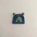 Detailaufnahme der blauen Baby-Strickmütze mit 3D-Frosch-Aufnäher und Good-Stickerei - 1-3 Jahre (47-52cm) / Himmelblau
