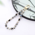 Close-up of handmade beaded phone strap with marble texture beads and golden spacers - K3423 Black White Fire Agate Natural Stone Pendant