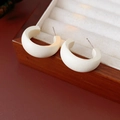 Detailed close-up of white wooden C-shaped earrings on a vintage jewelry case - C-Shaped Wooden Style / White
