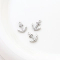 Detailed view of silver anchor charms with cubic zirconia on a white plate for DIY jewelry - 11# Silver Anchor