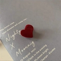 Dettaglio di una molletta a cuore in velluto rosso su una cartolina grigia retro - Cuore floccato rosso