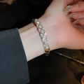 Dettaglio del bracciale incrociato in zircone argento con motivo a griglia sul polso femminile - Bracciale Rigido con Zirconi Trapuntato / Argento