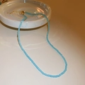 Minimalist blue beaded necklace with a golden lobster clasp on a ceramic tray - Blue Crystal Beads