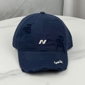 Close-up of distressed navy baseball cap with white N embroidery and ripped details - Navy Blue