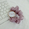 Nahaufnahme von elegantem lila Seiden-Scrunchie-Band und roségoldenem rundem Zifferblatt - Lila