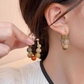 Colorful beaded hoop earrings with translucent stones and gold clasp on model - Green Agate