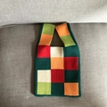 Top view of a colorful knitted heart tote bag on a grey fabric sofa with natural lighting - Green Checkerboard