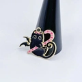 Cartoon black cat winged creature pin holding a pink candy cane on a display stand - Winged Black Cat